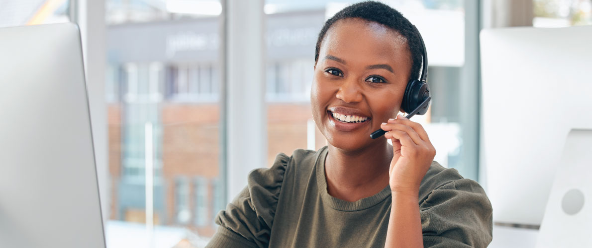 A woman smiling, wearing a headset for a phone call