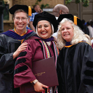 Law school student at graduation posing with two professors