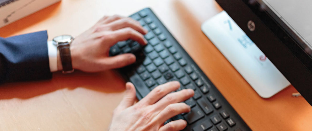 A man typing on his desktop computer